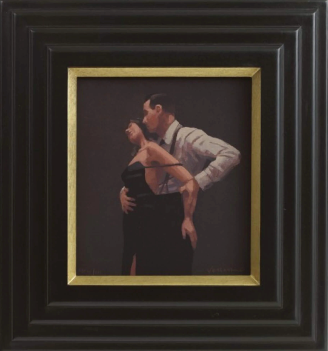 A framed painting of a couple embracing and kissing, with the man in a white shirt and the woman in a black dress, set within a gold inner frame and a wider black frame.