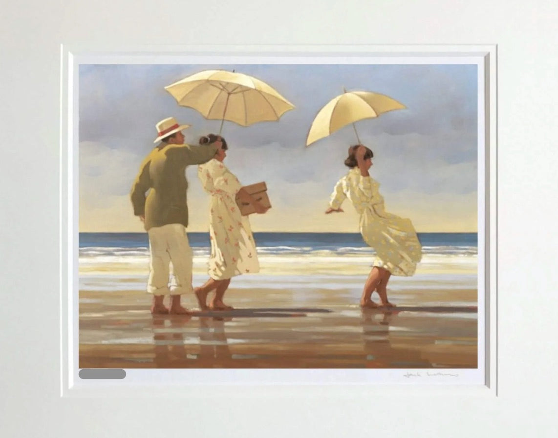 A framed art print depicting a beach scene with three people walking under cream-colored umbrellas on a sandy shore, with the ocean and cloudy sky in the background.